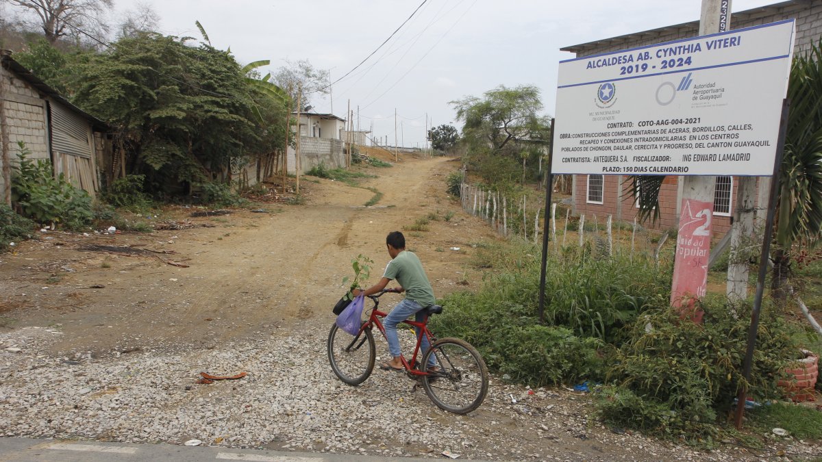 Obras. Las localidades al pie de un letrero que anuncia obras en la parroquia siguen en pura tierra.