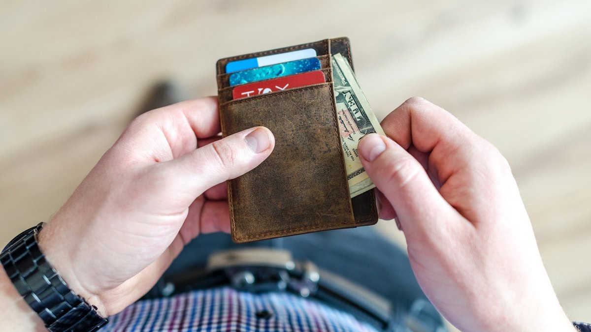 HOMBRE SOSTENIENDO BILLETERA CON TARJETAS Y DINERO EN EFECTIVO |