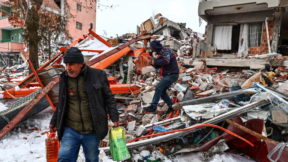 Personas transportan alimentos rescatados de un edificio derrumbado tras un fuerte terremoto en el distrito de Elbistan de Kahramanmaras, sureste de Turquía, el 07 de febrero de 2023.