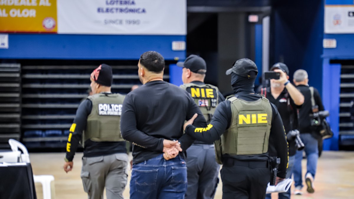 Varios  agentes mientras acompañan a una de las personas arrestadas durante un operativo