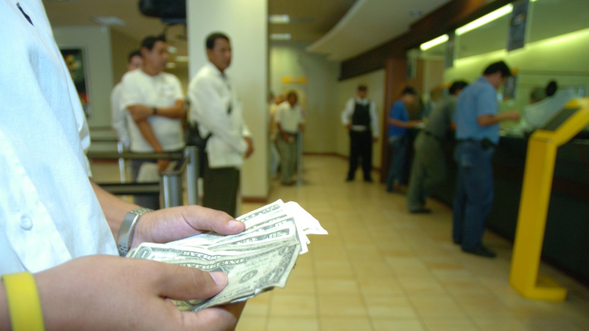 Dinero.- Una persona cuenta los dólares que ha recibido en un banco.