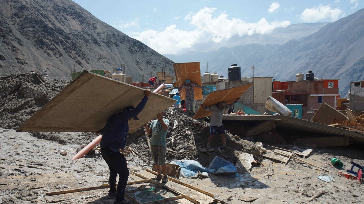 Personas caminan entre los escombros ocasionados por el alud en el pueblo de Secocha en Arequipa (Perú).