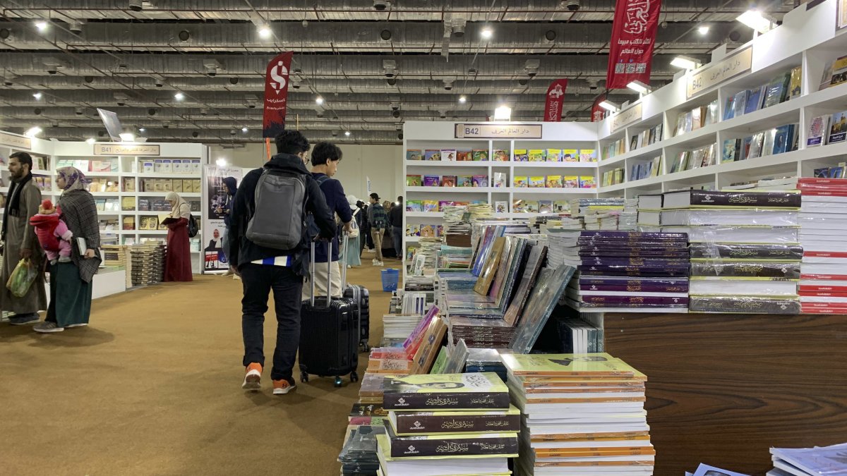 Pistas. Jóvenes en maletas llevan libros comprados en feria de El Cairo.