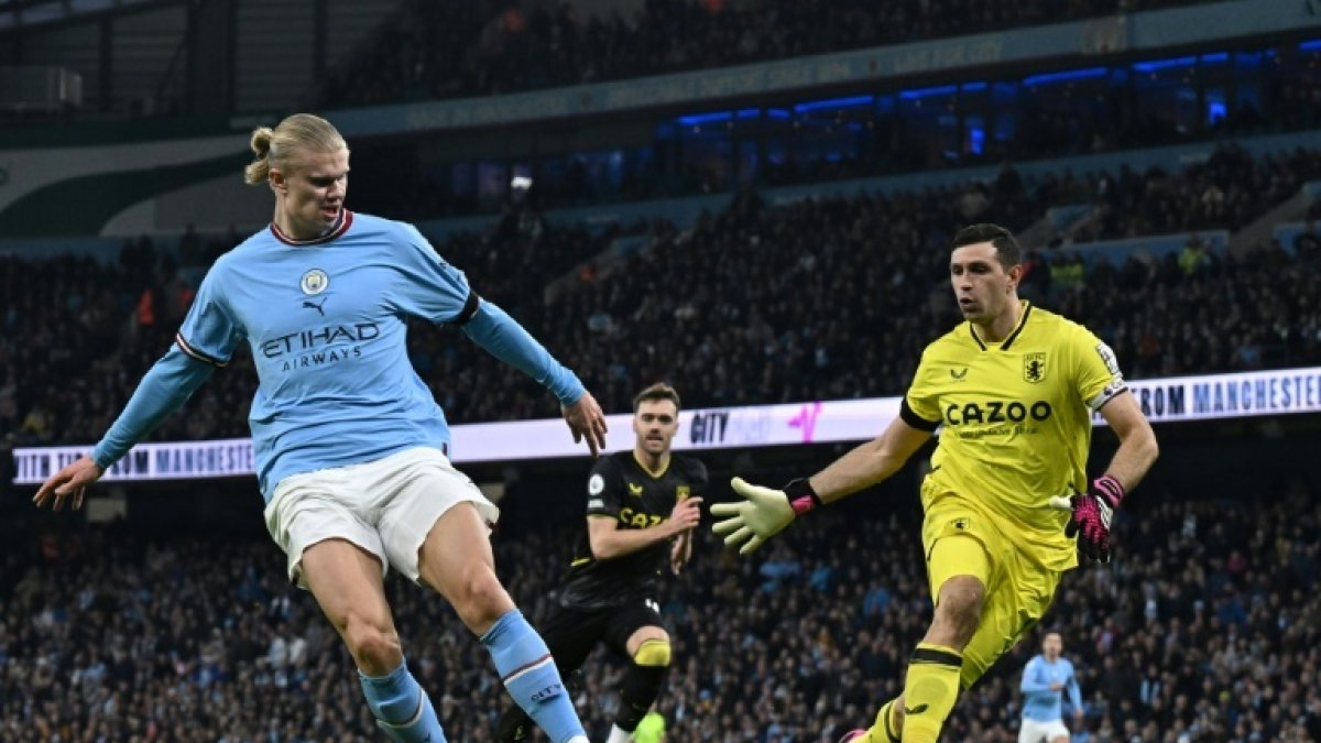 El delantero noruego Erling Haaland (i) elude la marca del portero del Aston Villa, Emiliano Martínez (d).