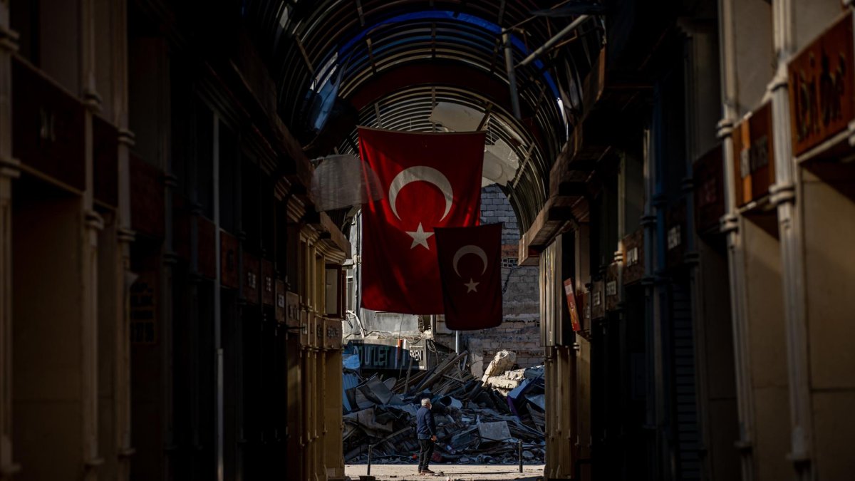 Un hombre se encuentra en medio de una calle junto a un edificio derrumbado tras un fuerte terremoto, en la ciudad de Hatay, Turquía, el 14 de febrero de 2023.