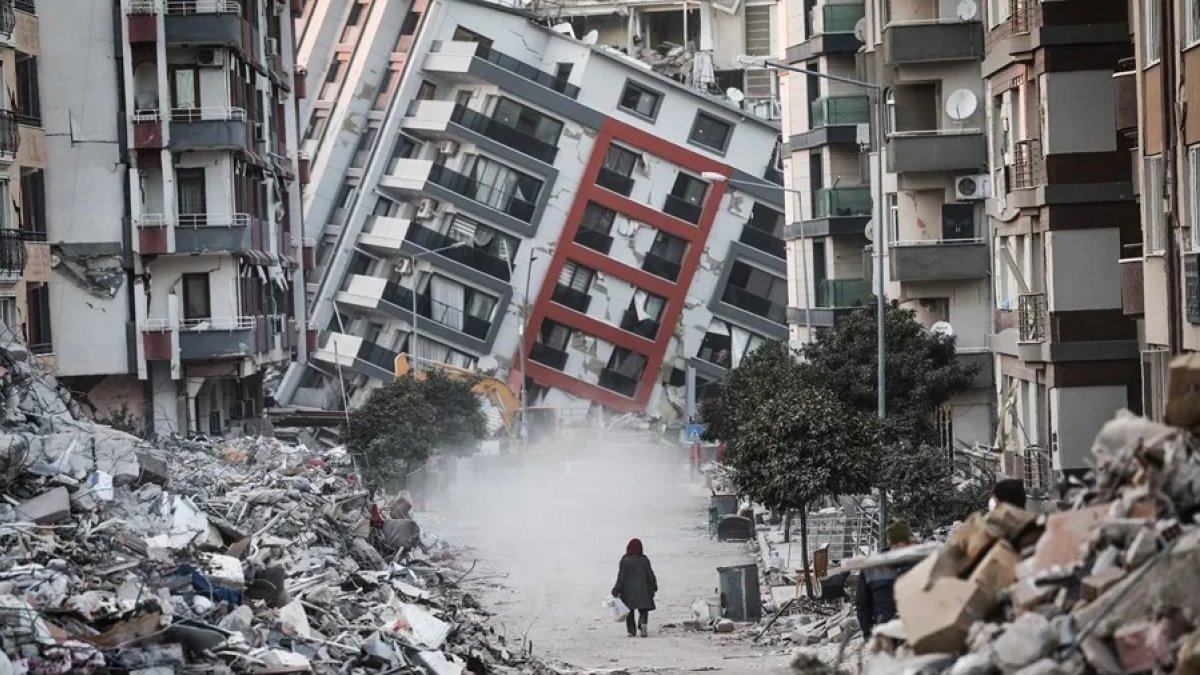 Una mujer pasa junto a edificios en ruinas, tras los terremotos de Turquía.
