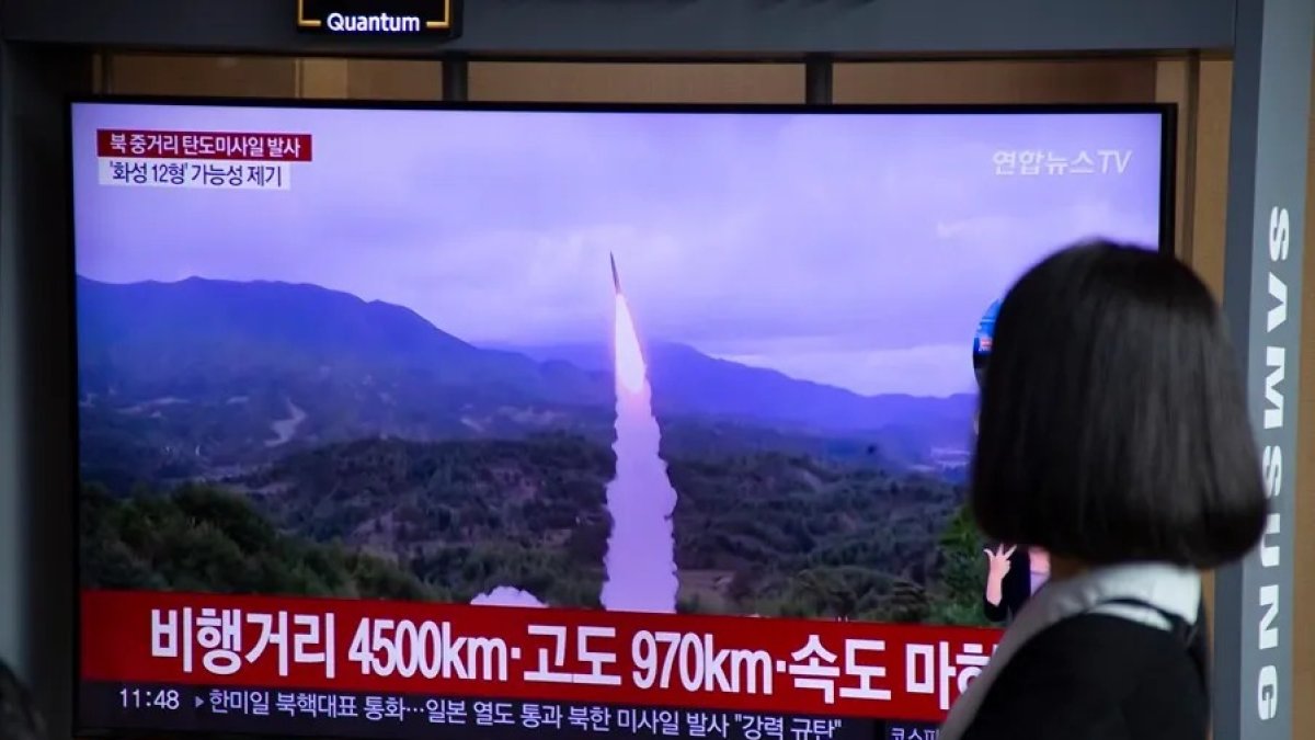 Una mujer observa un misil balístico de Corea del Norte en un lanzamiento anterior.