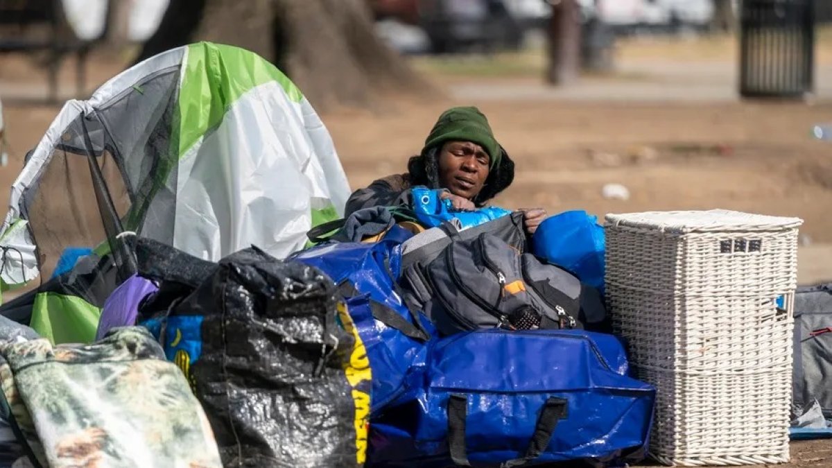 Una mujer sin hogar empaca sus pertenencias antes de que los miembros de un equipo de limpieza del Servicio de Parques Nacionales desalojen un campamento para personas sin hogar.