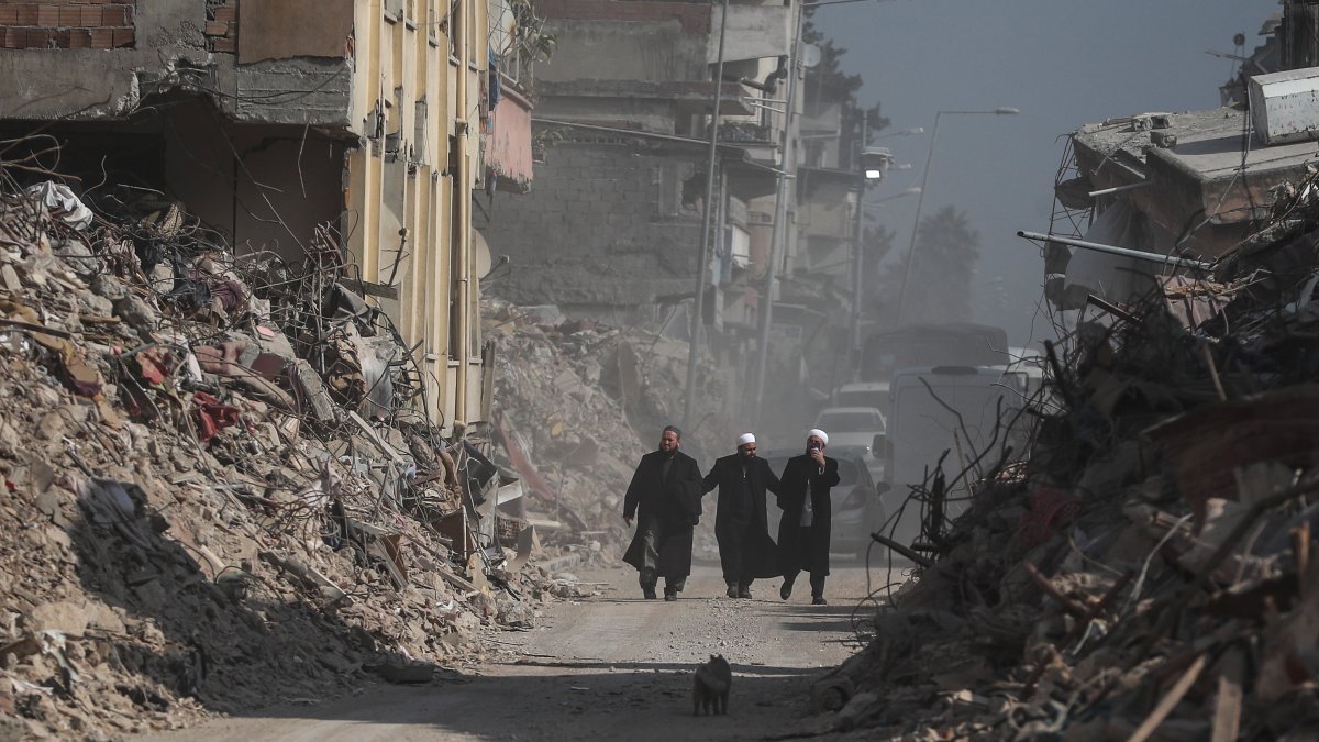 La gente pasa frente a los edificios derrumbados tras los fuertes terremotos en Hatay, Turquía, el 23 de febrero de 2023.