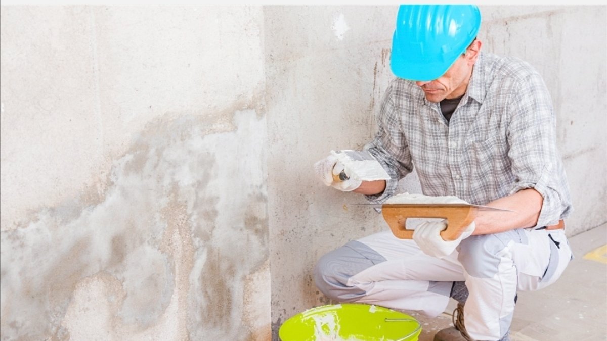 Obra. Un maestro de construcción arregla una pared que tiene humedad.