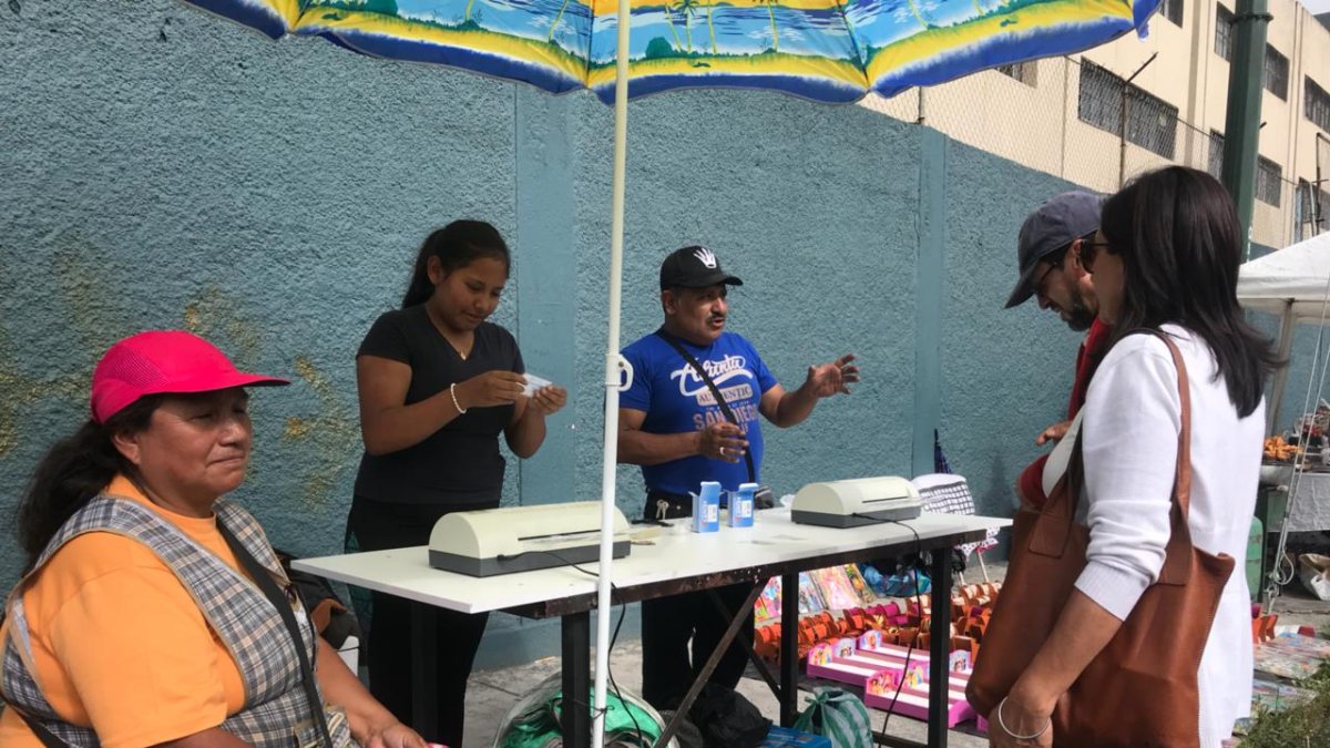Una postal tradicional del día de elecciones. Personas ofrecen emplasticar el certificado de votación.