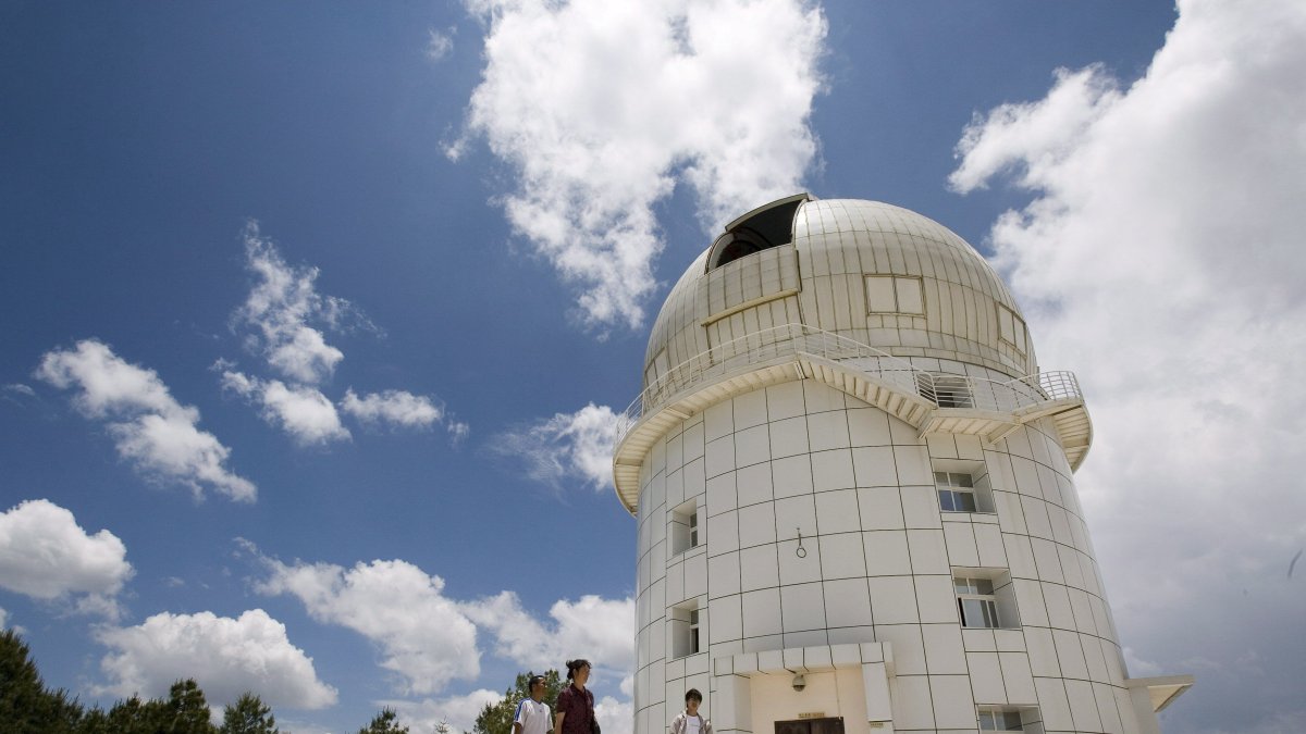Tres personas caminan frente al observatorio Gaomeigu, fuera de Lijiang al suroeste de la provincia china de Yunnan, uno de los mayores del este de Asia . 