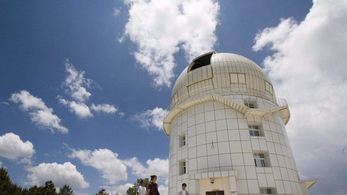Tres personas caminan frente al observatorio Gaomeigu, fuera de Lijiang al suroeste de la provincia china de Yunnan, uno de los mayores del este de Asia .
