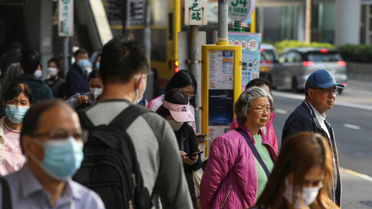 Viajeros, algunos de ellos todavía con mascarillas, esperan en una parada de autobús en Hong Kong, China, 01 de marzo de 2023