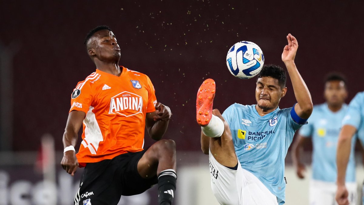 Kevin Minda (d) de Católica disputa un balón con Jader Valencia de Millonarios.