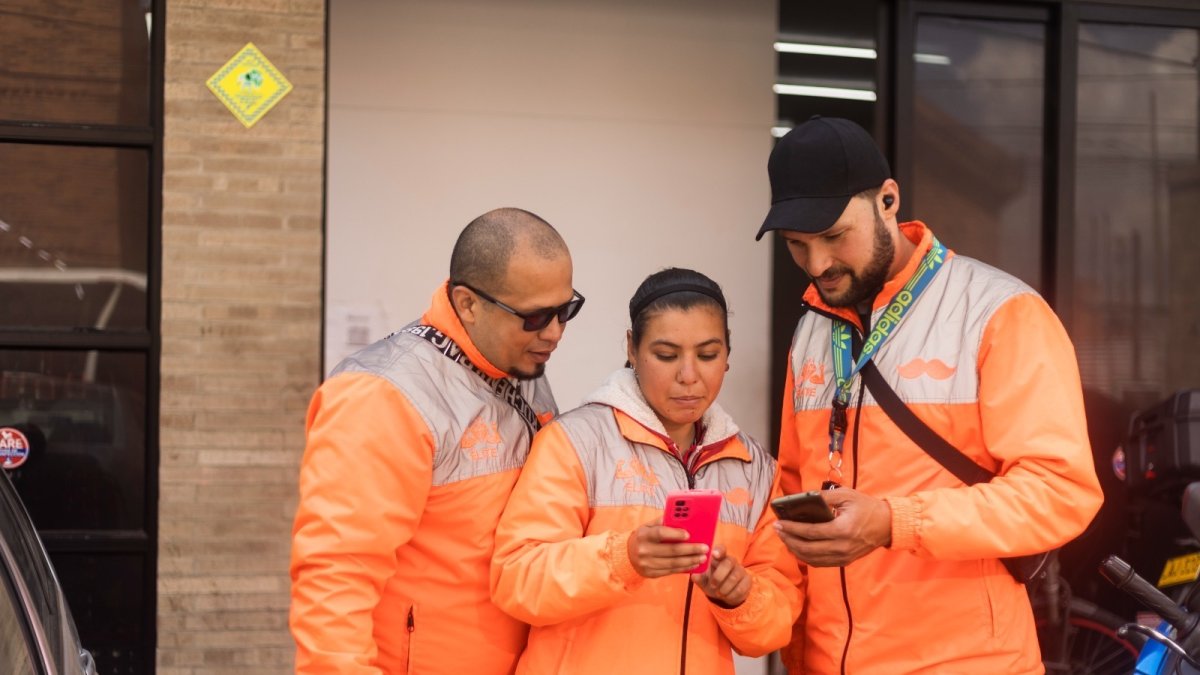 Trabajadores.- Tres personas revisan la aplicación de delivery con la que laboran.