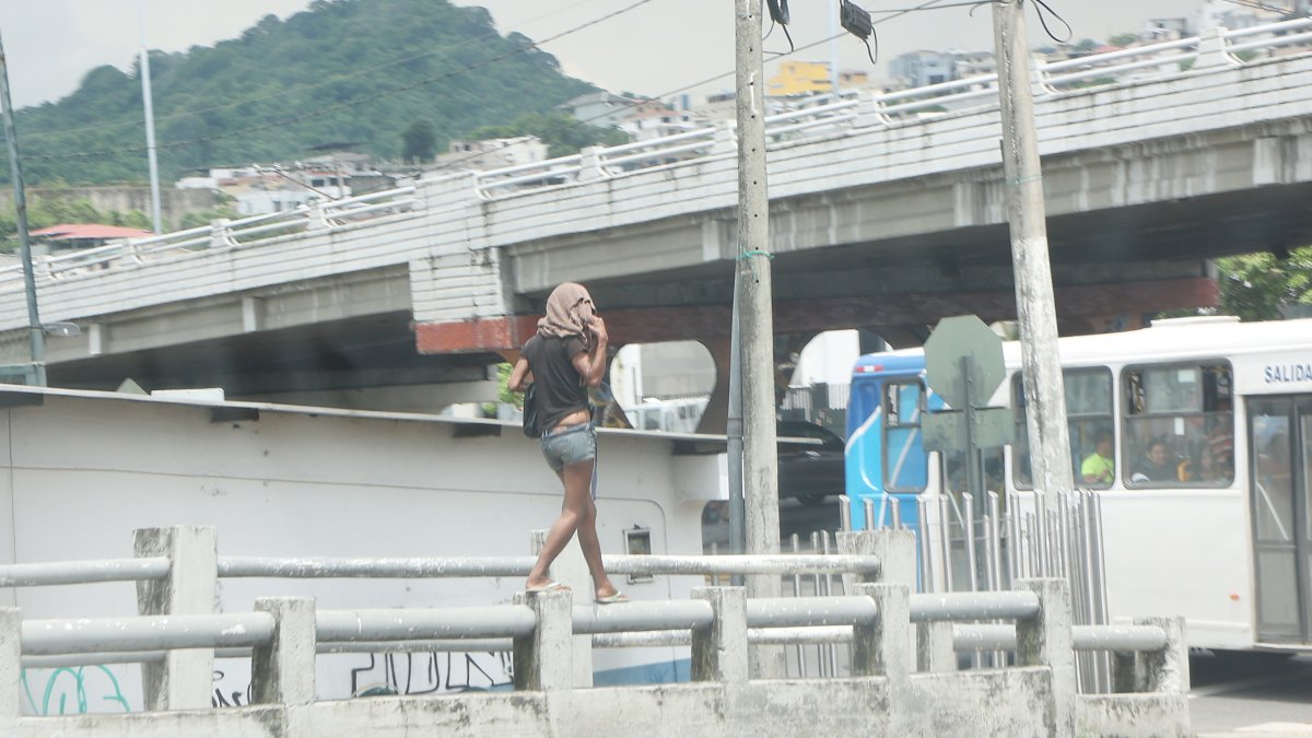 Un mujer camina sobre el tubo de un puente en el norte de la ciudad.