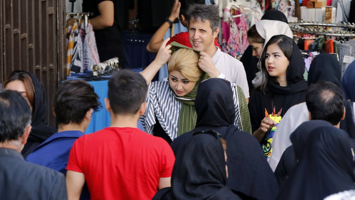 Una mujer se ajusta el velo, mientras camina por una calle