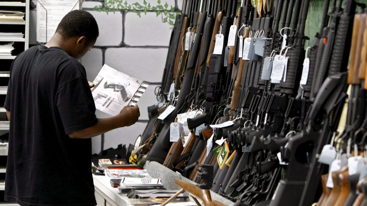 Fotografía de archivo en la que se registró a un hombre al detallar el manual de un pistola, dentro de una tienda de armas, en Kansas (EE.UU.). 