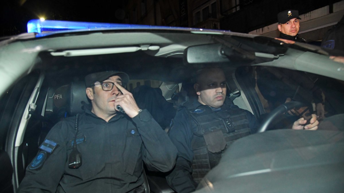 Fotografía de archivo, tomada el pasado 2 de septiembre, en la que se registró a dosagentes de la Policía Federal de Argentina al trasladar a Fernando Sabag Montiel (c, cubierto),