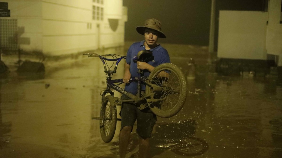 Pobladores de Punta Hermosa al sur de Lima, caminan en el lodo que inundó las calles hoy martes 14 de marzo en Lima (Perú).