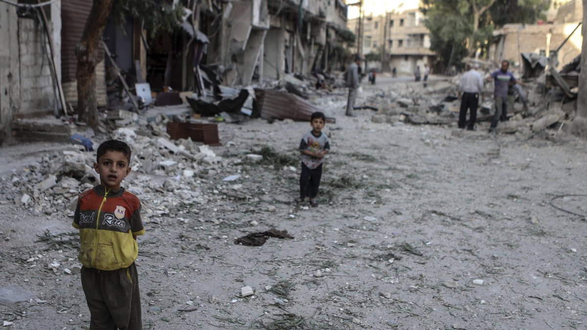 Imagen de archivo de niños delante de viviendas destruídas por bombardeos en Arbin, a las afueras de Damasco (Siria). EFE/Mohammed Badra