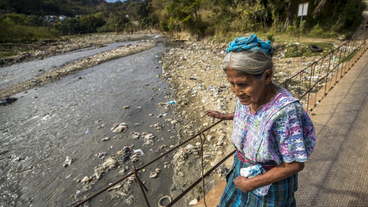 Una mujer cruza el río Las Vacas que transporta cientos de toneladas de basura, el 13 de febrero 2023, provenientes de la Ciudad de Guatemala, en Chinautla (Guatemala).