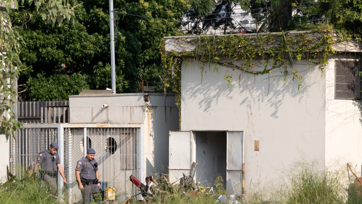 Miembros de los bomberos asisten al lugar donde un helicóptero cayó hoy en un barrio de la zona oeste de Sao Paulo (Brasil).