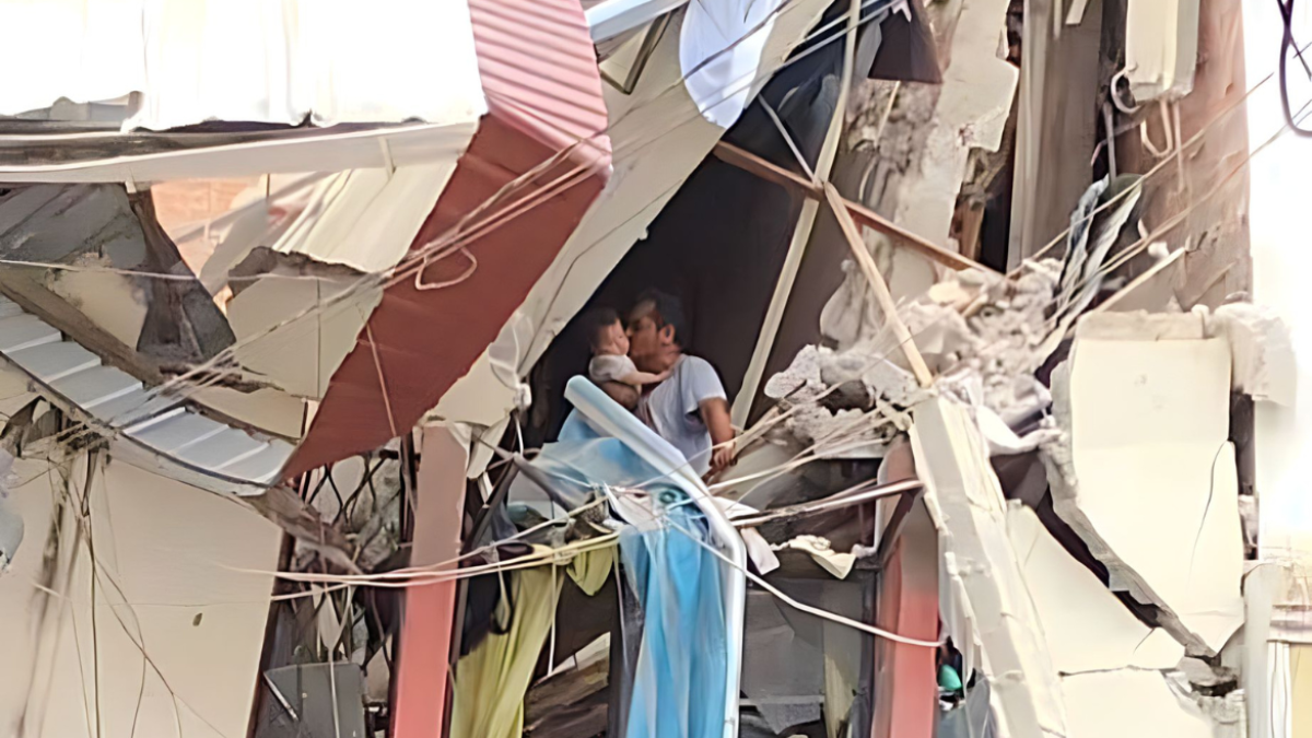 Escenario. Es un hombre, aferrádose a lo que queda de una pared y con los pies sobre una casa a punto de derrumbarse, pero quien se muestra feliz de que la vida que carga en sus brazos esté intacta.
