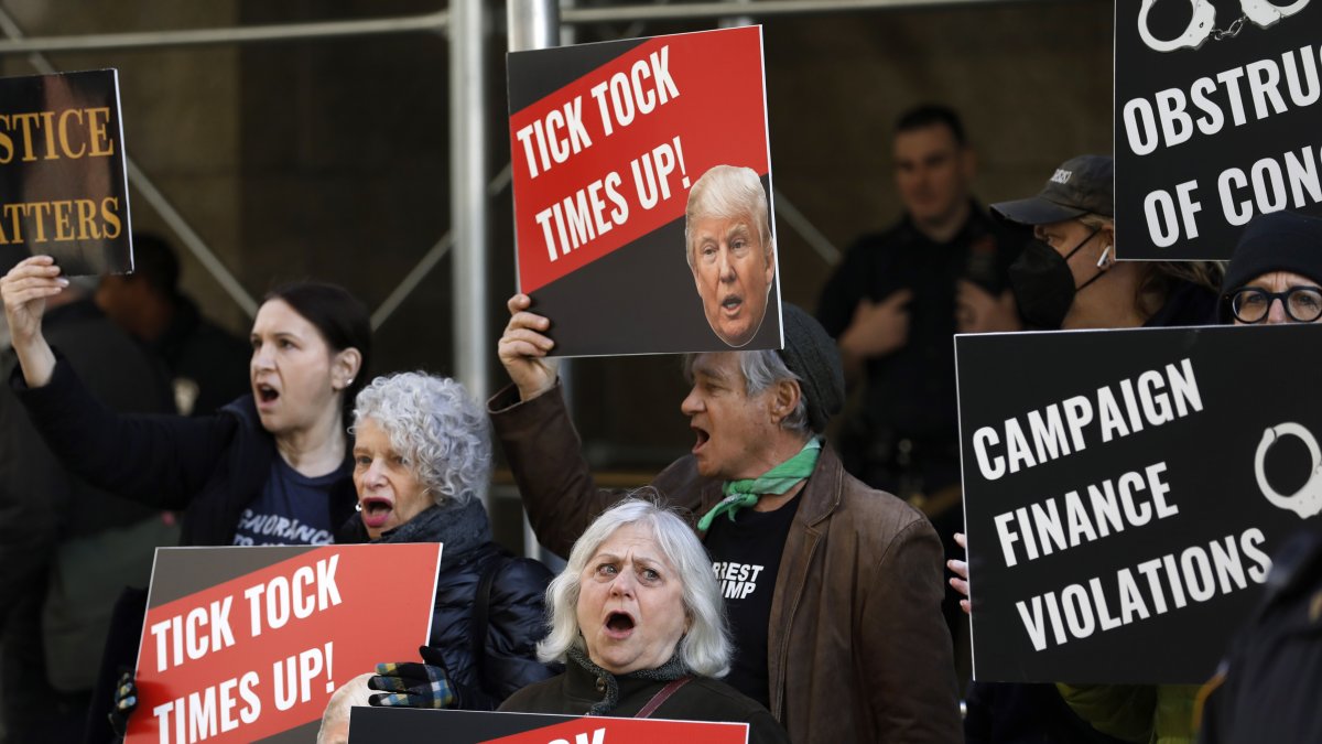 Manifestantes gritan y sostienen carteles frente al Tribunal Penal de Nueva York antes de una posible acusación contra el expresidente Donald Trump en Nueva York, Nueva York.