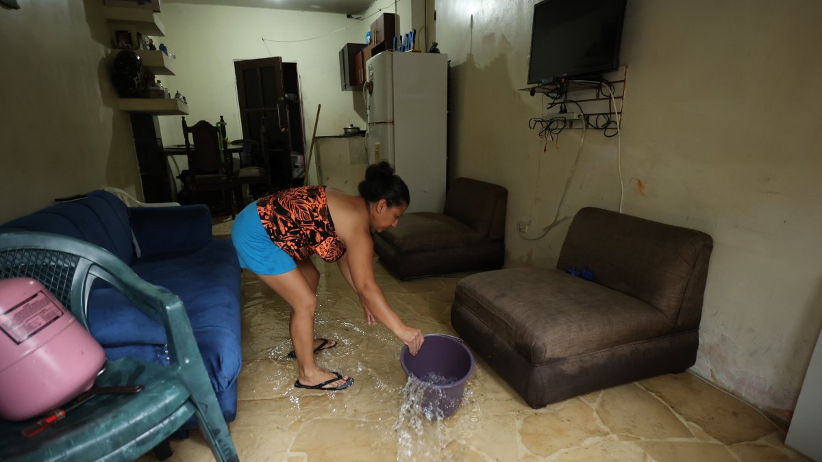 Inundación. Una ama de casa saca el agua que se metió a su casa por la lluvia y aguaje que hubo en Guayaquil, sus enseres se afectaron.