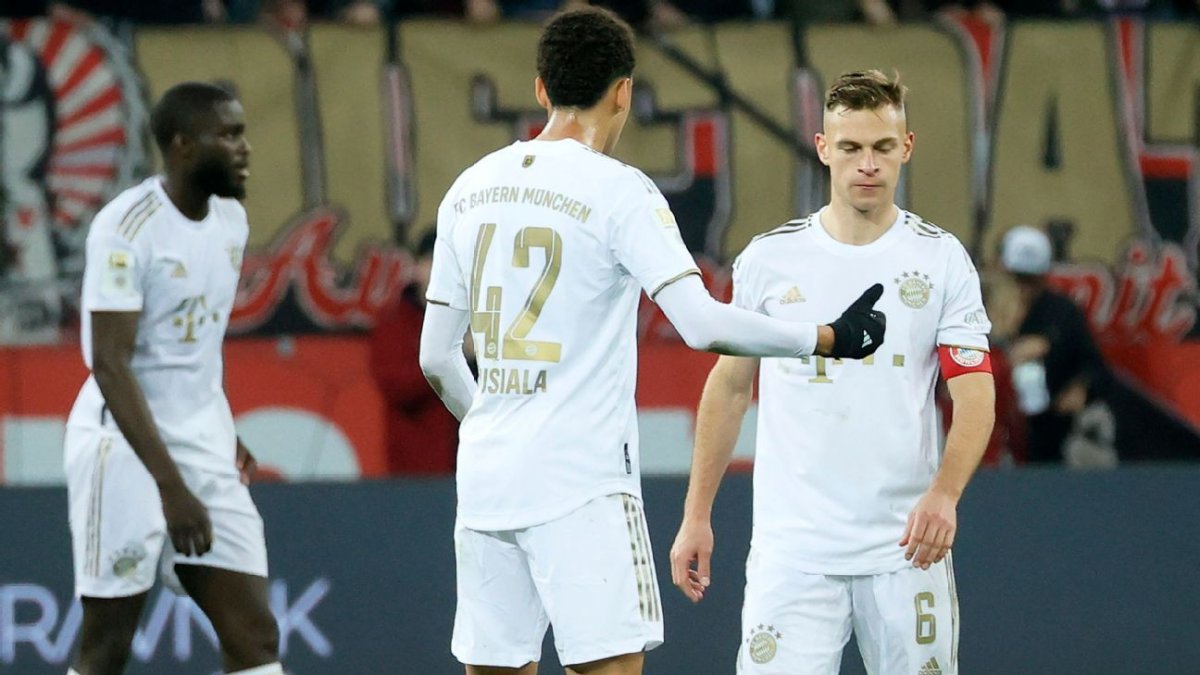 Joshua Kimmich (d) capitán del Bayern Múnich, recibe indicaciones de su compañero Jamal Musiala (c).