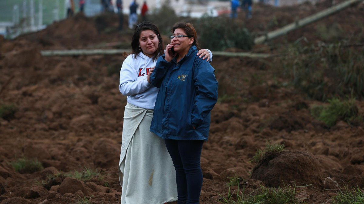 Familiares se lamentan hoy en la zona donde se presentó un deslizamiento de tierra, en Alausí (Ecuador).