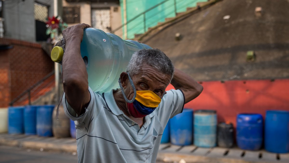 Caracas. Un hombre al cargar un botellón de agua potable suministrado por un camión cisterna en un barrio popular de esta capital sudamericana.