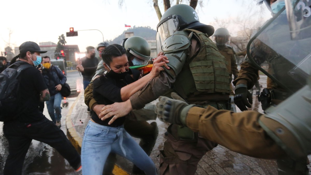Fotografía de archivo fechada el 4 de septiembre de 2020 que muestra a carabineros mientras forcejean con una manifestante, en la Plaza Italia de Santiago (Chile). 