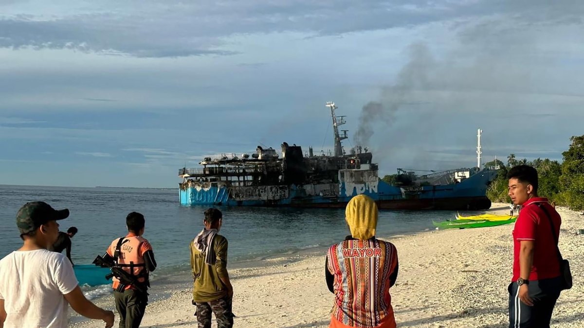 Un grupo de personas observa el incendio en el ferri de pasajeros en Basilan.