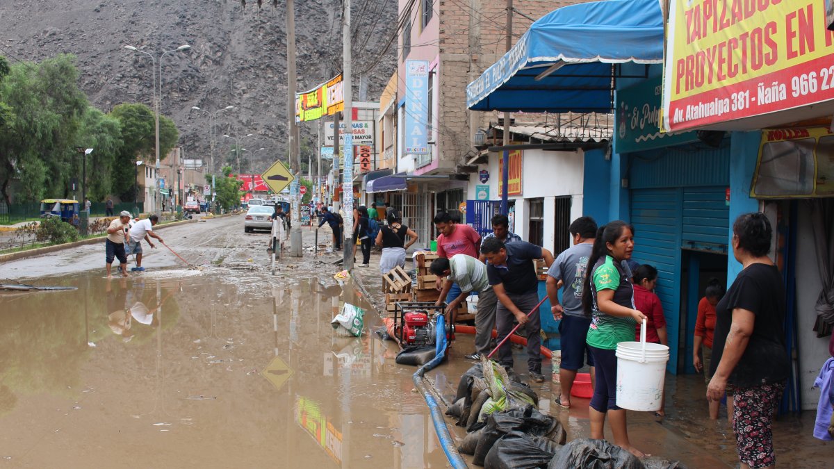 Residentes intentan sacar el agua de sus casas y locales inundados por el ciclón Yaku, en el distrito de Chaclacayo, en Lima.