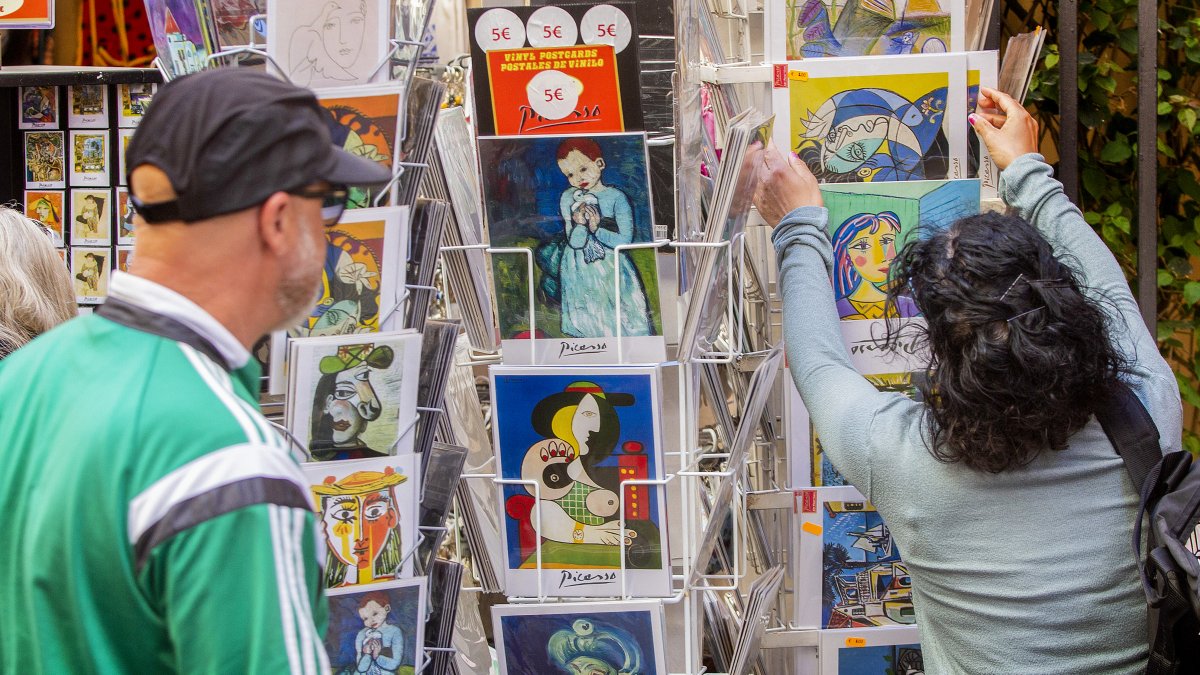 Escena. Unos turistas miran postales con obras del pintor Pablo Ruiz Picasso en el entorno del museo que lleva su nombre en el centro de la ciudad de Málaga.