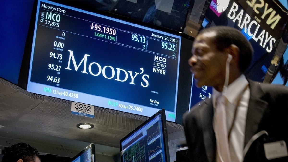 Bolsa.- Una pantalla muestra la información del ticker de Moody's mientras los operadores trabajan en el piso de la Bolsa.