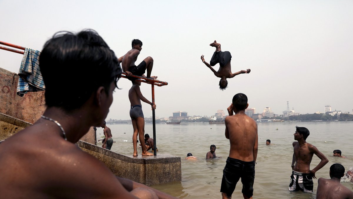 Niños indios saltan al río Ganges mientras se refrescan durante una calurosa tarde en Calcuta, India, el 18 de abril de 2023.