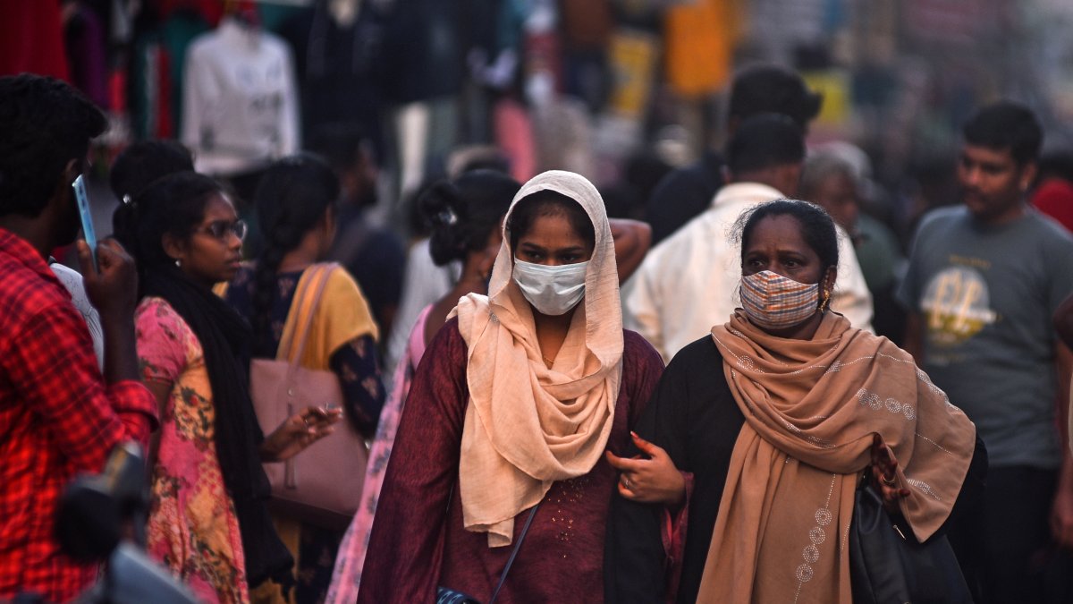 Dos mujeres con mascarilla pasan por una calle llena de gente en Chennai, India, el 11 de abril de 2023. 
