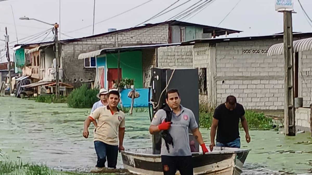 En Santa Lucía, un grupo traslada en una canoa los electrodomésticos desde un sector anegado.