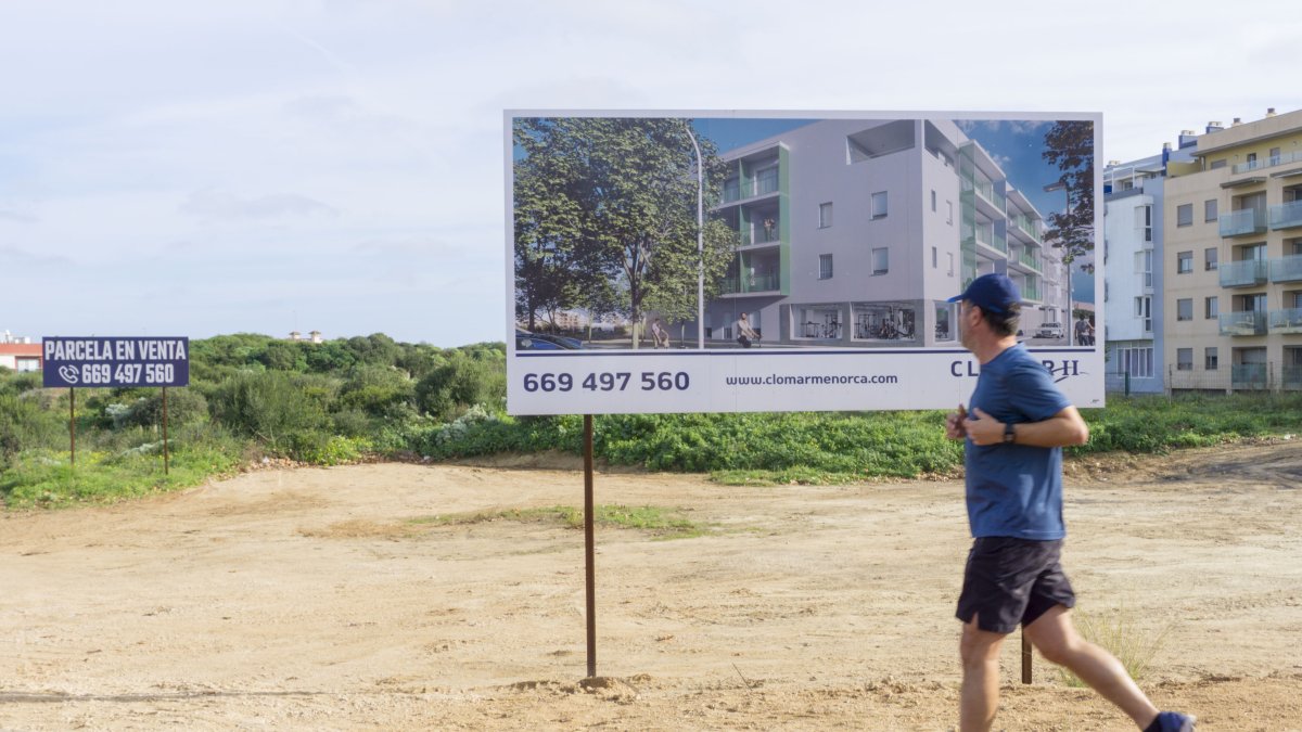 Un hombre pasa frente a una publicidad de venta de obra nueva en Maó, Menorca, este lunes.