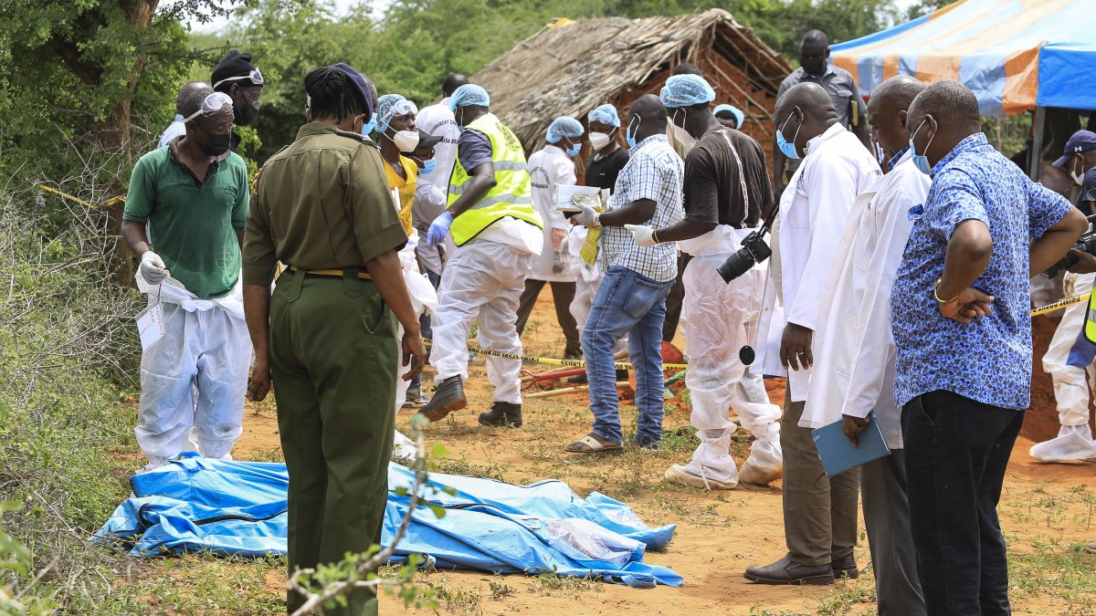 Detectives de homicidios de Kenia y expertos forenses de la Dirección de Investigaciones Criminales (DCI), examinan los cuerpos exhumados de varias fosas comunes