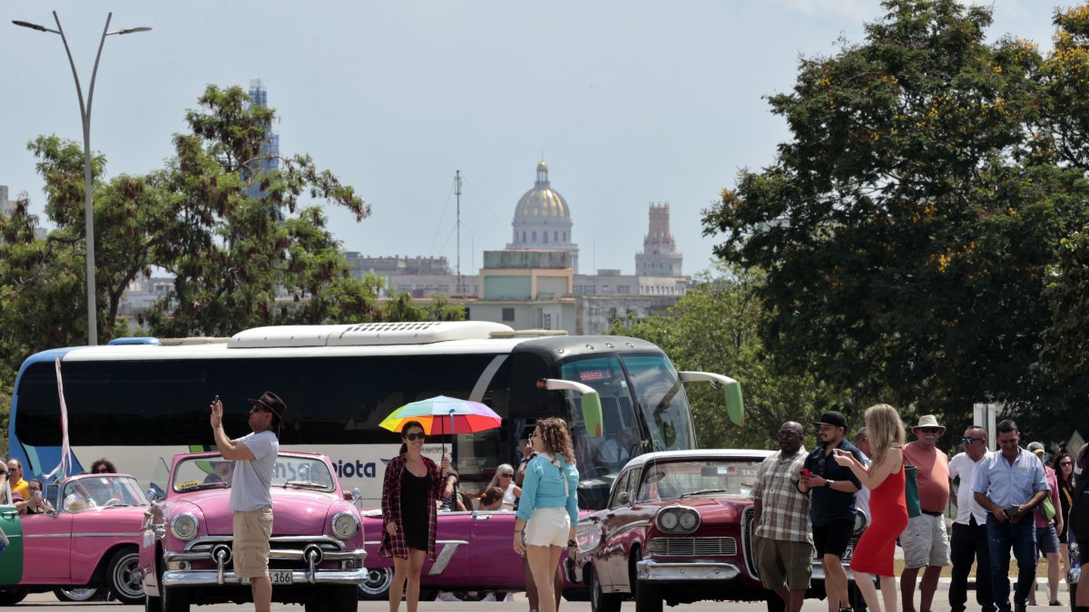 Escena. Turistas se toman fotografías con autos clásicos, el 28 de abril de 2023 en La Habana (Cuba). 