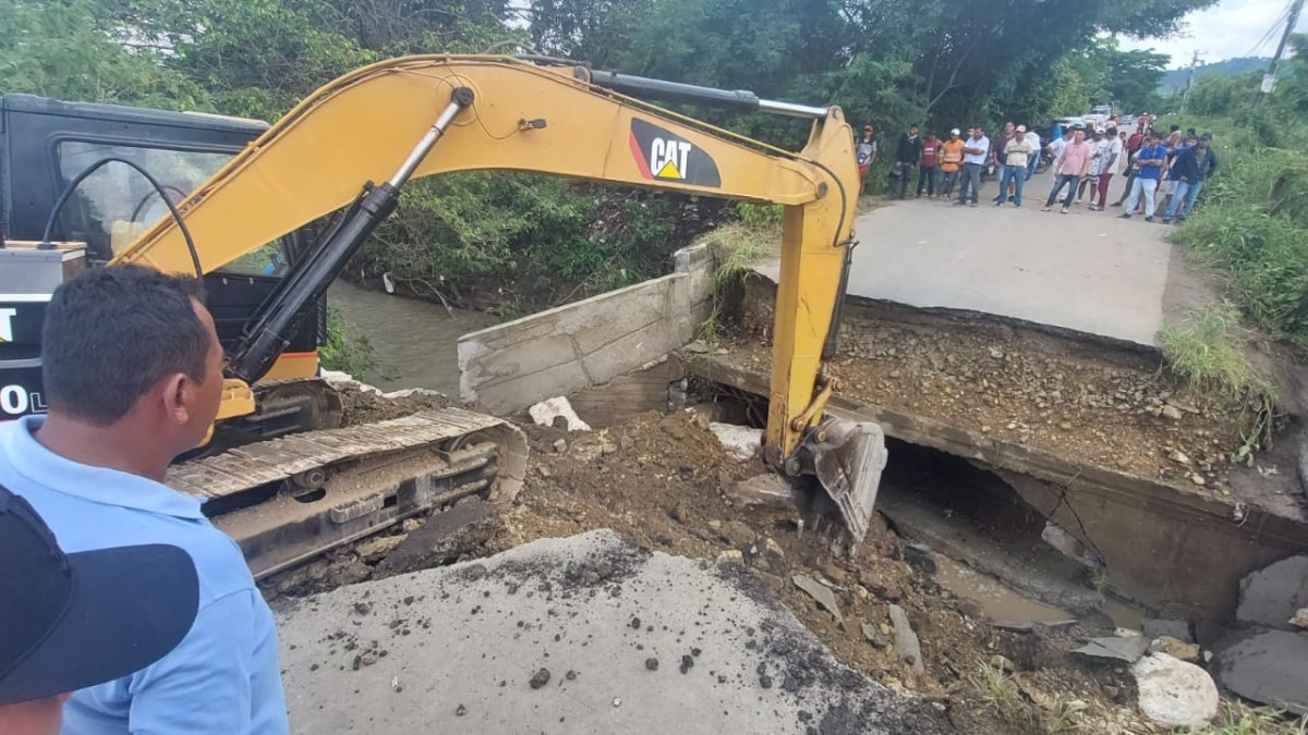 Una retroexcavadora prepara el terreno para levantar un paso vehicular temporal.