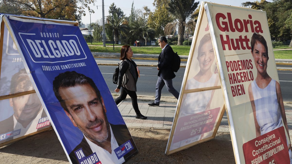 Personas caminan frente a carteles de propaganda electoral para consejeros Constitucionales, el 27 de abril 2023, en Santiago (Chile).