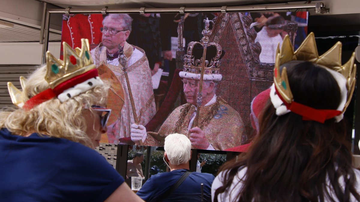 Un grupo de turistas británicos este sábado en Magaluf (Calviá, Baleares), sigue en directo la coronación del rey Carlos III, con coronas de juguete en la cabeza.