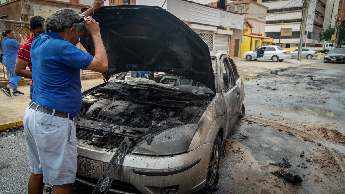 Un hombre observa un vehículo quemado en Maracaibo (Venezuela.)