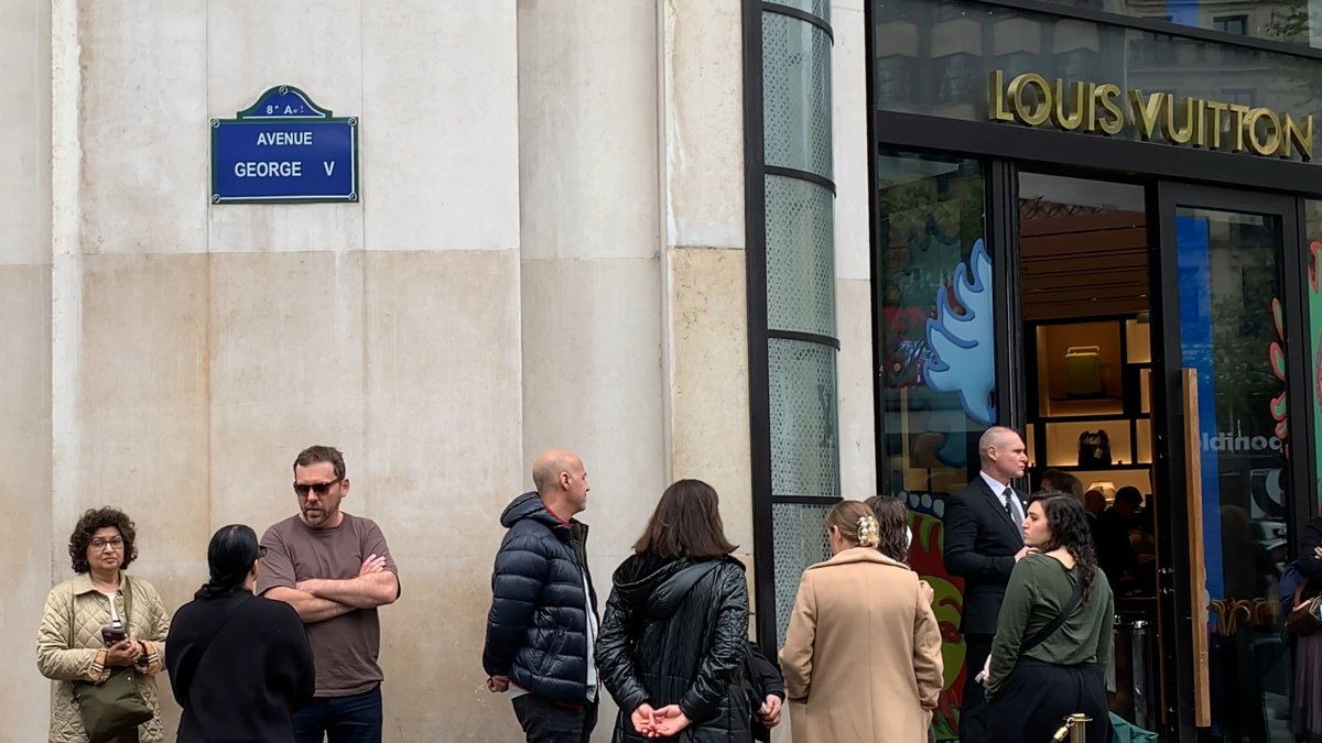 Varias personas esperan en la puerta de una tienda de lujo este sábado en París.